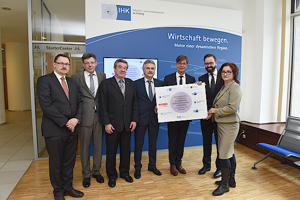 Das Bild zeigt den Schirmherrn des Bündnisses, den Sächsischen Staatsminister der Justiz, Sebastian Gemkow, gemeinsam mit Vertretern der beteiligten Institutionen in der IHK zu Leipzig und das Logo der Initiative.
