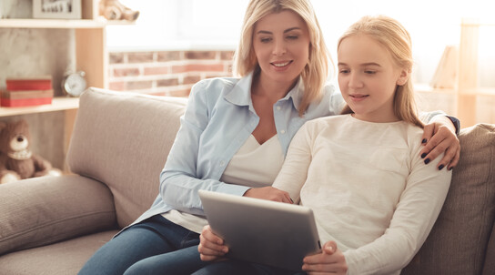 Mutter und Tochter sitzen mit iPad auf der Couch